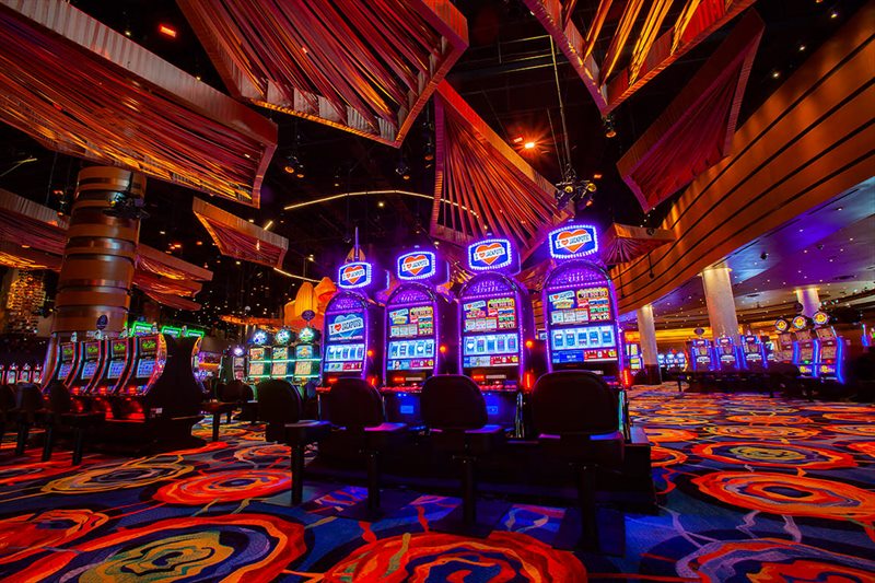 Fila de máquinas tragamonedas encendidas en la sala de un casino
